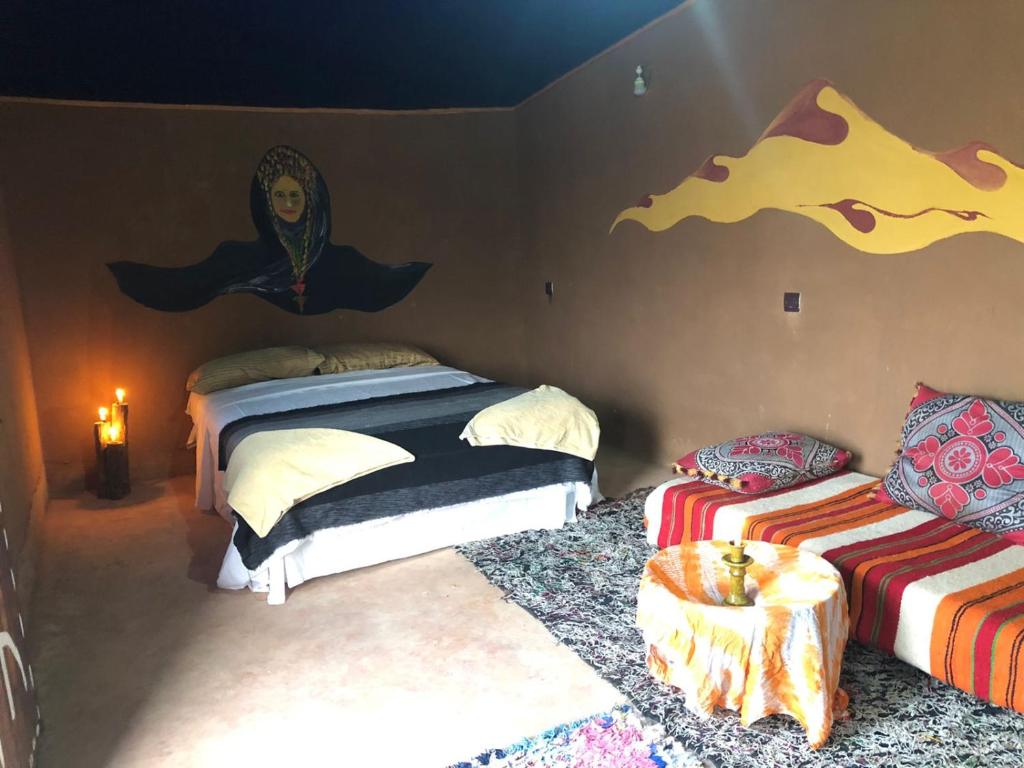 a bedroom with two beds and a painting on the wall at Sahara Authentic Berber Camp in Mhamid