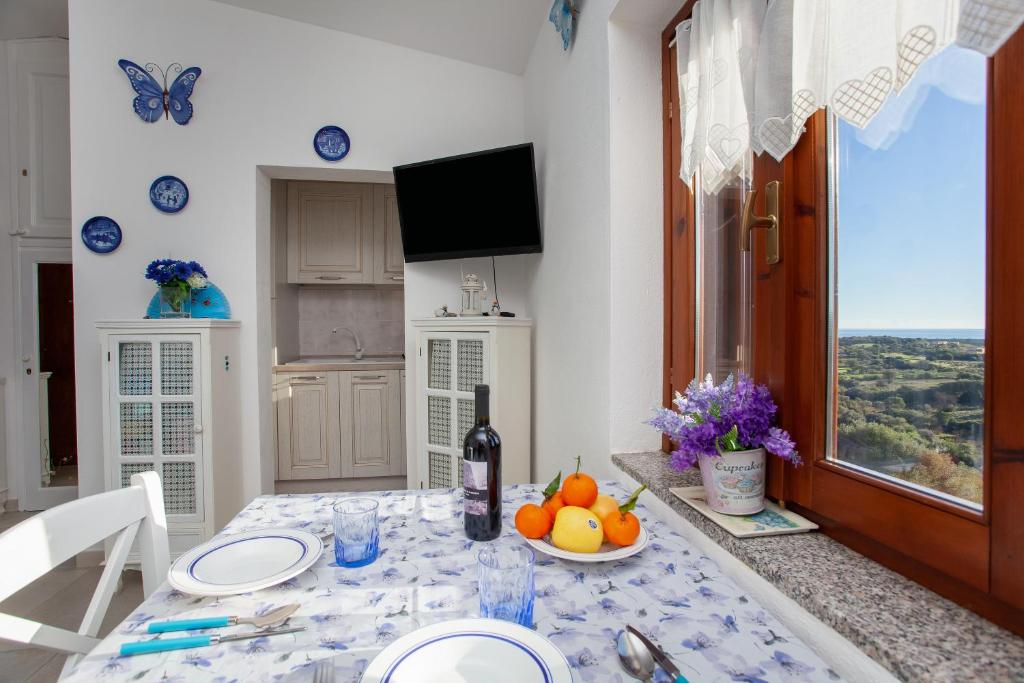 uma sala de jantar com uma mesa e uma garrafa de vinho em La finestra sul mare em Budoni
