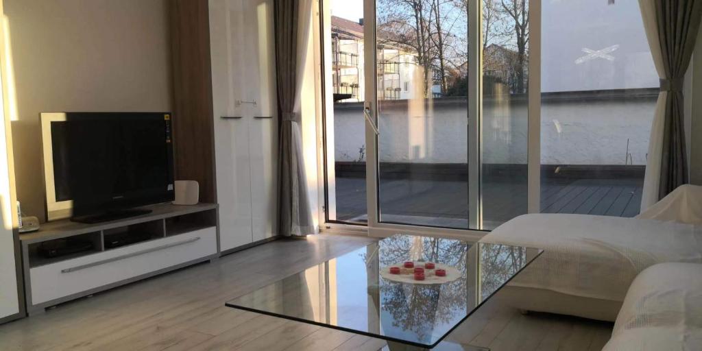 uma sala de estar com uma televisão e uma mesa de vidro em Traumhafte Ferienwohnung mit drei Schlafzimmer em Biebrich