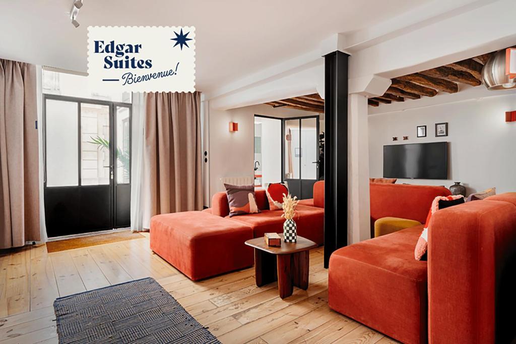 a living room with orange furniture and a tv at Edgar Suites Marais - Nazareth in Paris