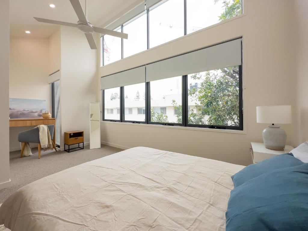 a bedroom with a large bed with a large window at Unique Kirra townhouse in Gold Coast