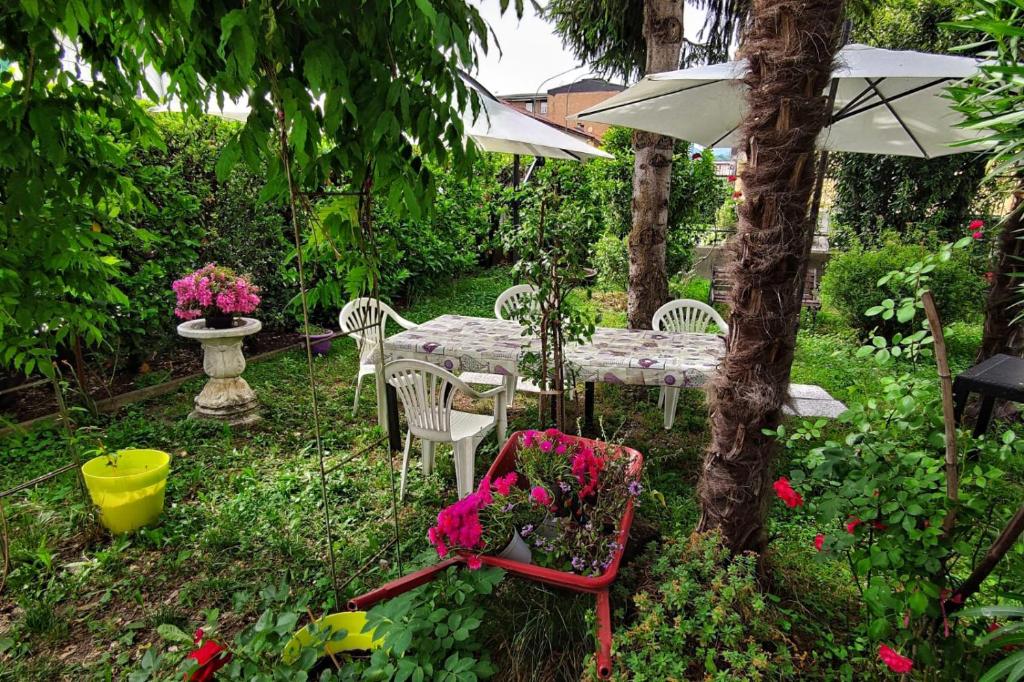 un tavolo con sedie e ombrellone in giardino di Da Simona- casa 4 posti letto + 4 aggiuntivi ad Arona