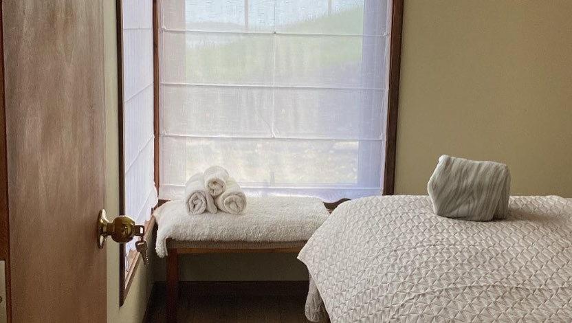 1 Schlafzimmer mit 2 Betten und einem Fenster mit Handtüchern in der Unterkunft Cabañas Las Terrazas De Iculpe in Lago Ranco