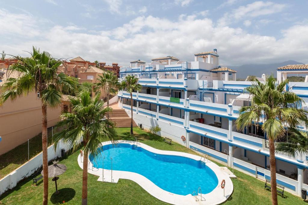 ein Apartmentgebäude mit einem Pool und Palmen in der Unterkunft Casa Carmen in Estepona