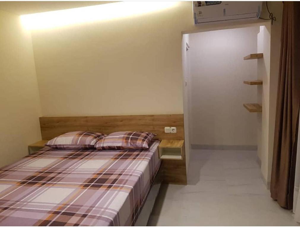 een slaapkamer met een bed en een deur naar een kast bij Lauwrens Guest House in Makassar