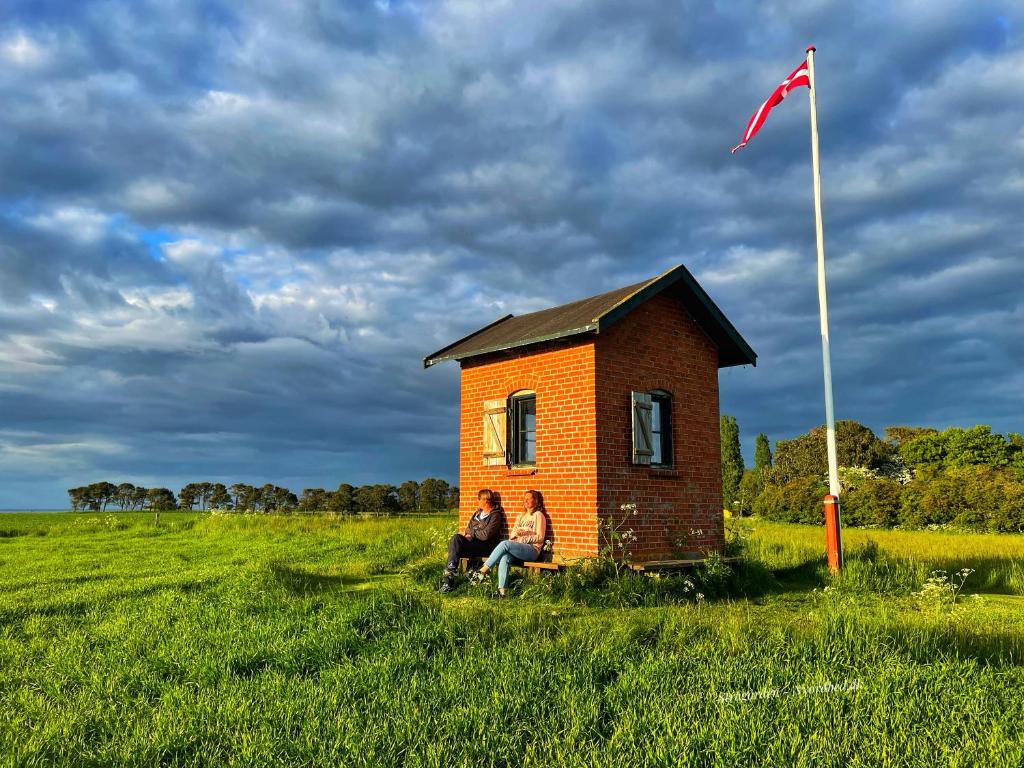 2 personnes assises dans une petite maison dans un champ dans l'établissement Sovgodt Nyord, à Nyord