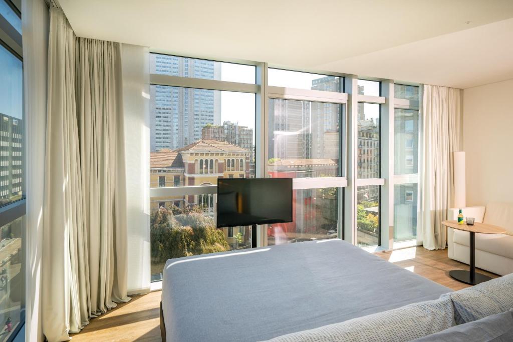 - une chambre avec un grand lit et de grandes fenêtres dans l'établissement INNSiDE by Meliá Milano Torre GalFa, à Milan