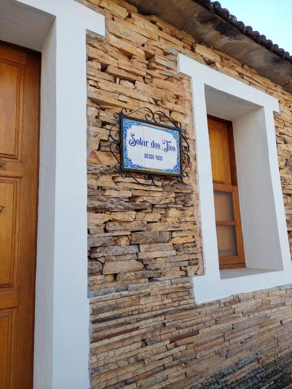 a stone wall with a sign on a building at Solar dos Tios in São Thomé das Letras