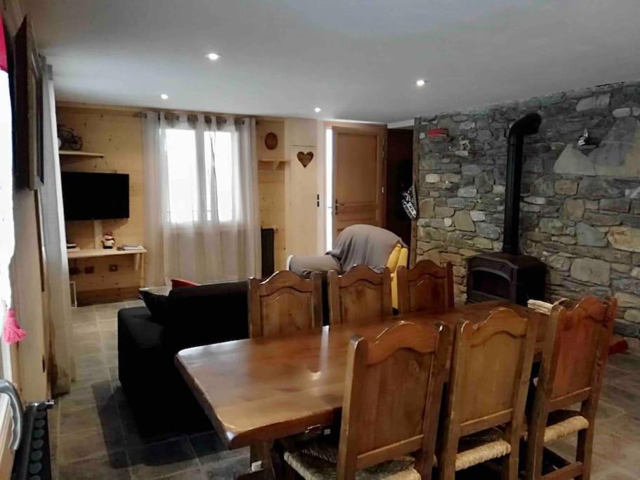 sala de estar con mesa de madera y pared de piedra en Chalet des Fées , 2 chambre ,70m2 ,navette gratuite,, en Les Avanchers