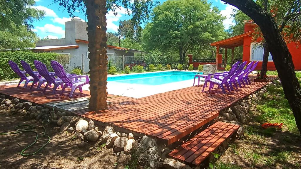 una terraza con sillas moradas junto a una piscina en Casa bela energia en Villa Las Rosas
