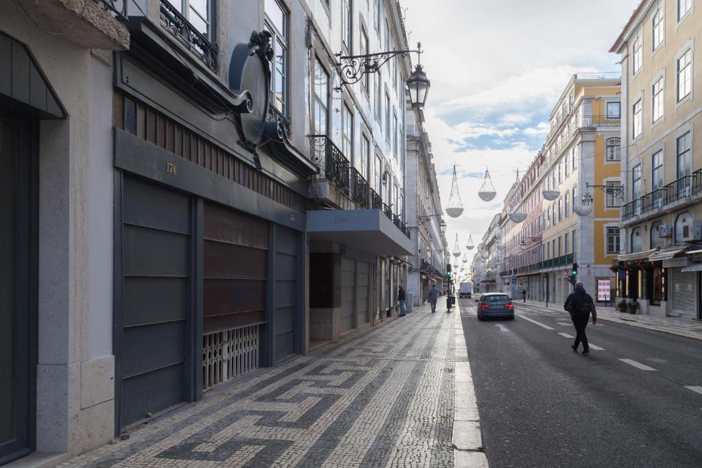 a person walking down a city street with buildings at FLH Downtown Marble Apartment in Lisbon