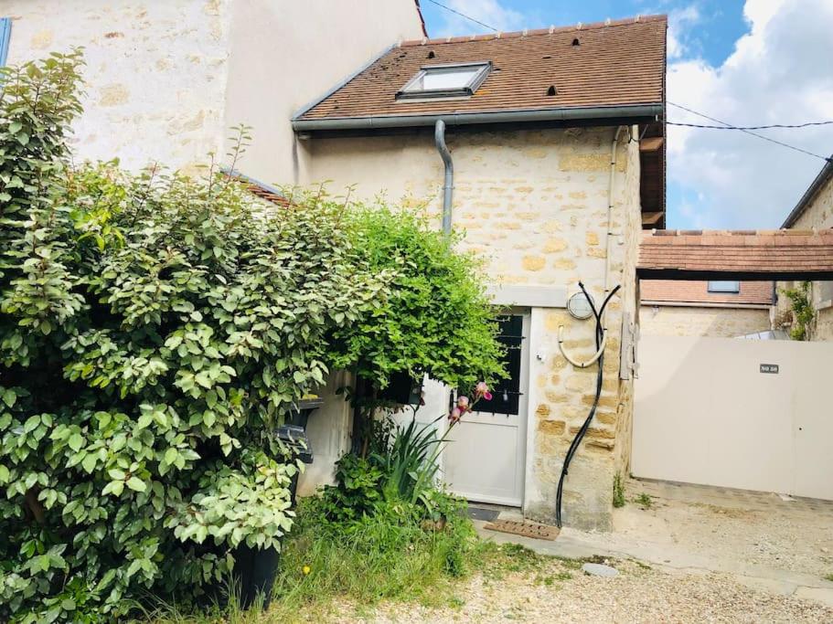 un bâtiment avec une porte blanche et un bush dans l'établissement Cocooning little house in french Vexin, à Us