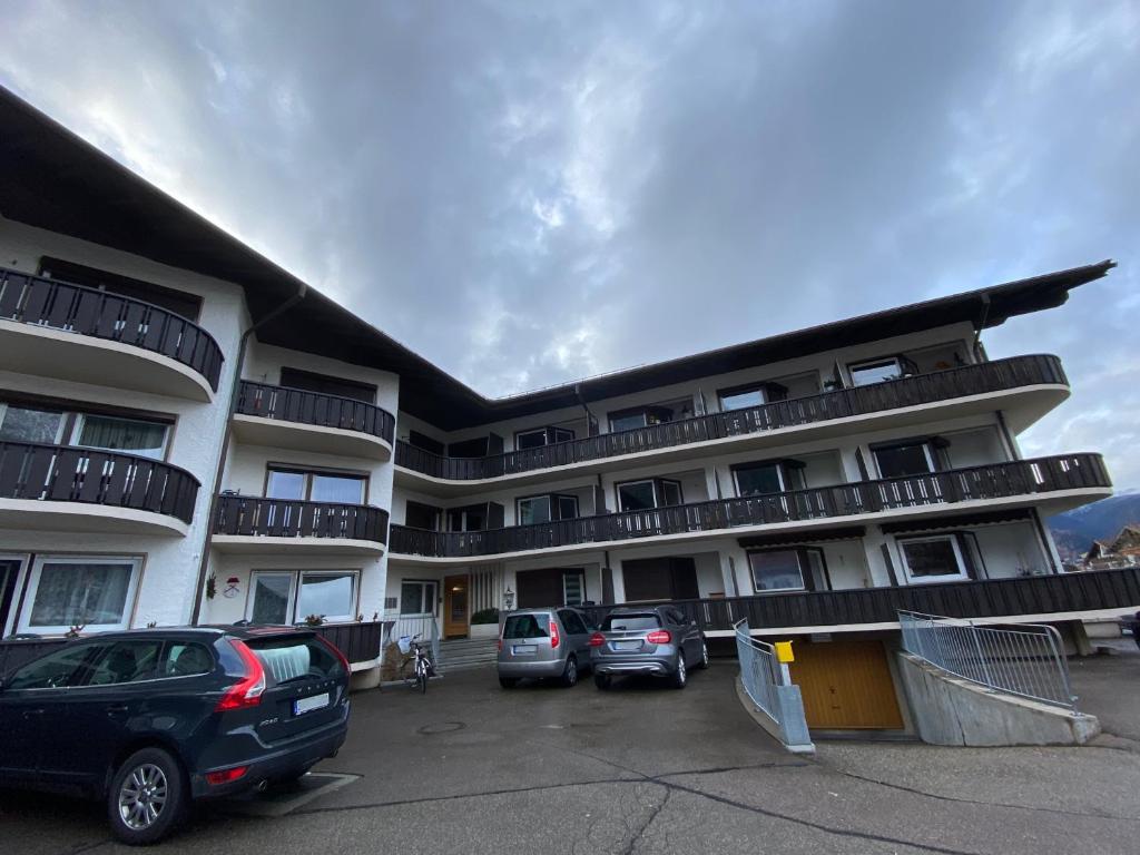 un gran edificio de apartamentos con coches aparcados en un aparcamiento en Studio Nebelhorn, en Oberstdorf