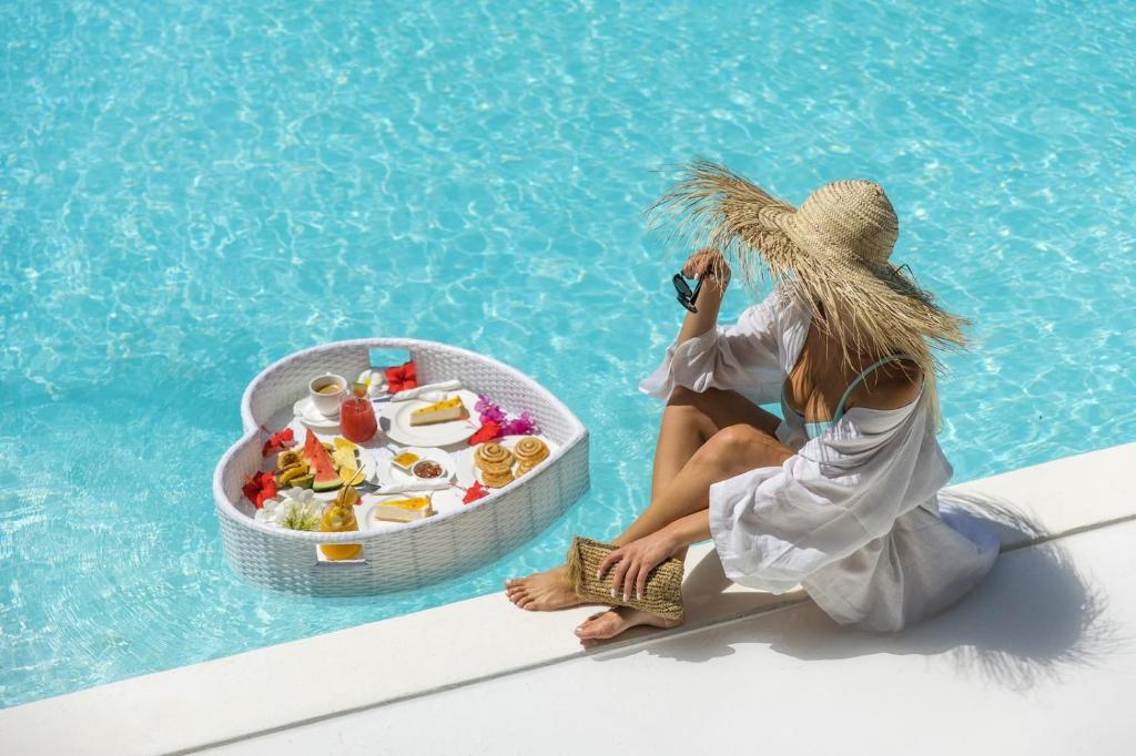 a woman in a straw hat sitting next to a swimming pool at Blue Moon Resort in Jambiani