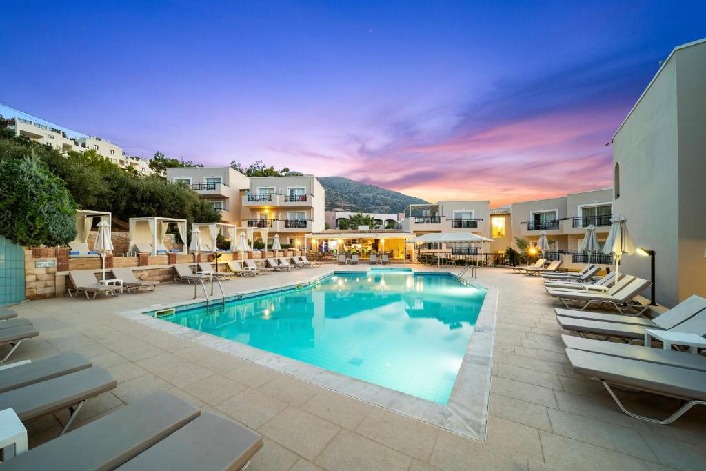 une piscine avec des chaises longues et un hôtel dans l'établissement Rainbow Apartments, à Stalida