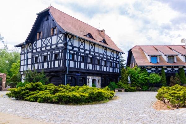 a large black and white building with a house at Karczma Rzym DWÓR in Wrocław