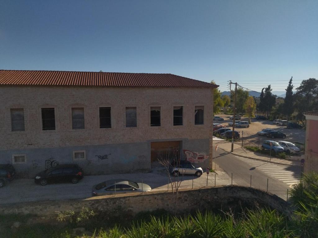 a building with cars parked in a parking lot at Captain's Rooms in Aegina Town