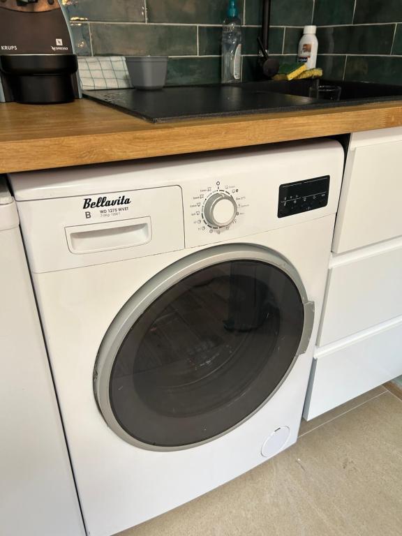 a white washer and dryer under a kitchen counter at Studio calme &amp; lumineux, vue sur le jardin, WIFI in Paris