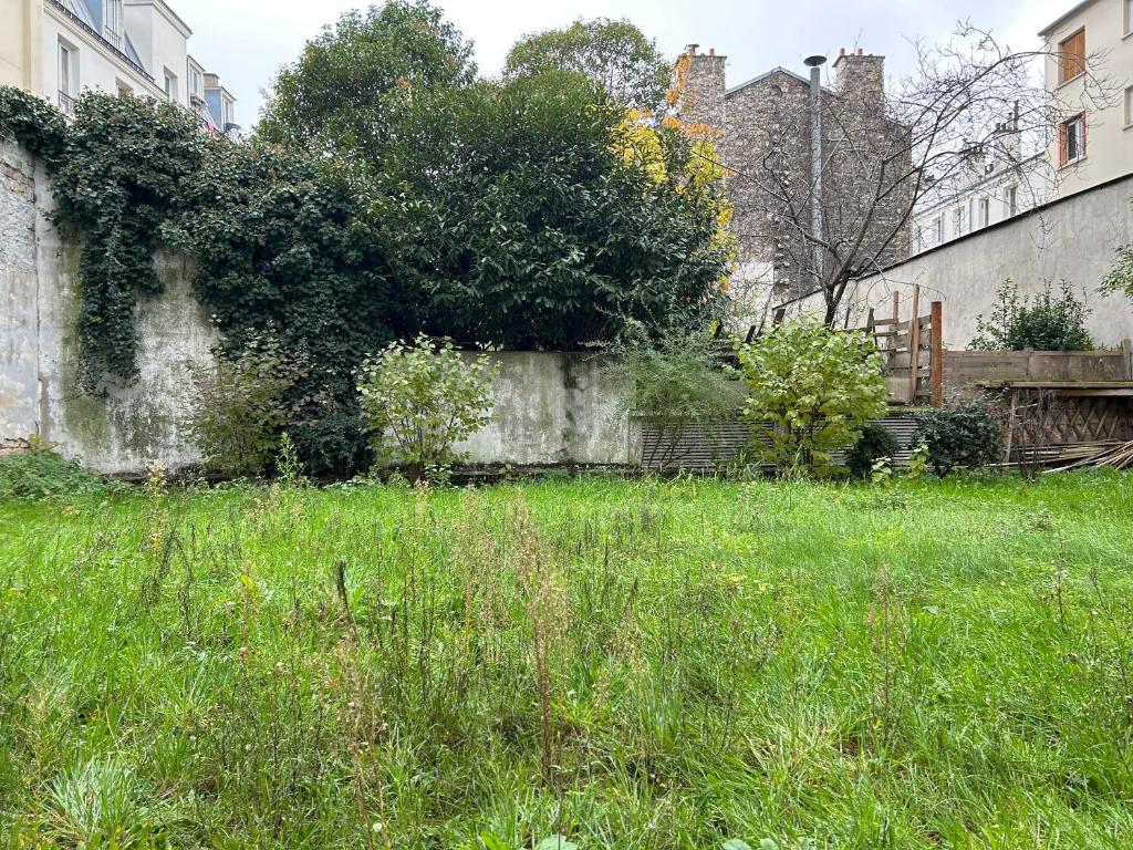 an old stone wall with green grass and weeds at Studio calme &amp; lumineux, vue sur le jardin, WIFI in Paris