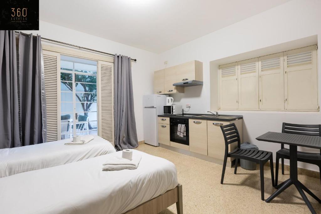 a room with two beds and a table and a kitchen at Spacious NUM1 house in Swieqi - Sleeps 18 w&#47;WIFI by 360 Estates in Is-Swieqi