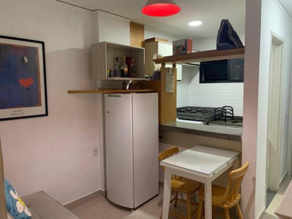 eine kleine Küche mit einem weißen Kühlschrank und einem Tisch in der Unterkunft Apartamento bairro Praia do Canto na Reta da Penha in Vitória
