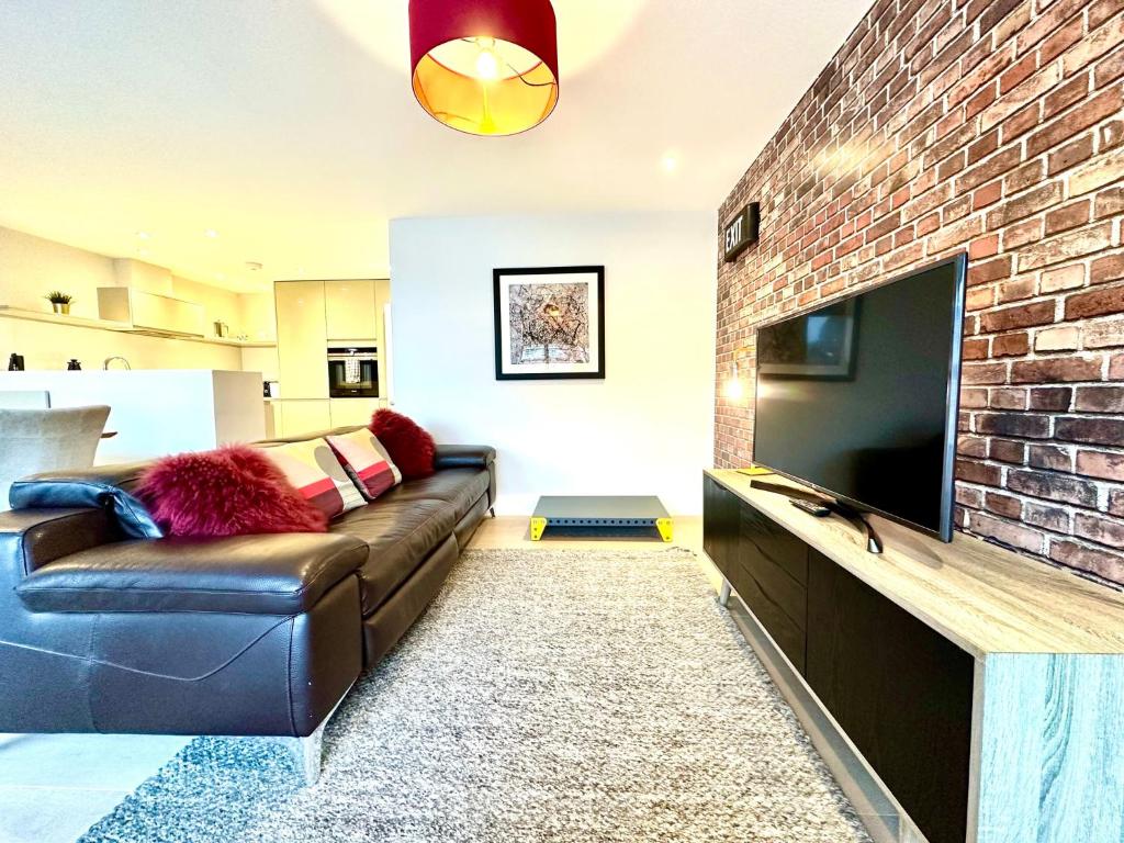 a living room with a couch and a brick wall at Beautiful New 2 Bedroom Apartment - Next to the Beach - Great Location - FREE Parking - Fast WiFi - Smart TV - sleeps up to 4! Close to Purbeck, Corfe Castle, Sandbanks, Poole & Bournemouth in Swanage