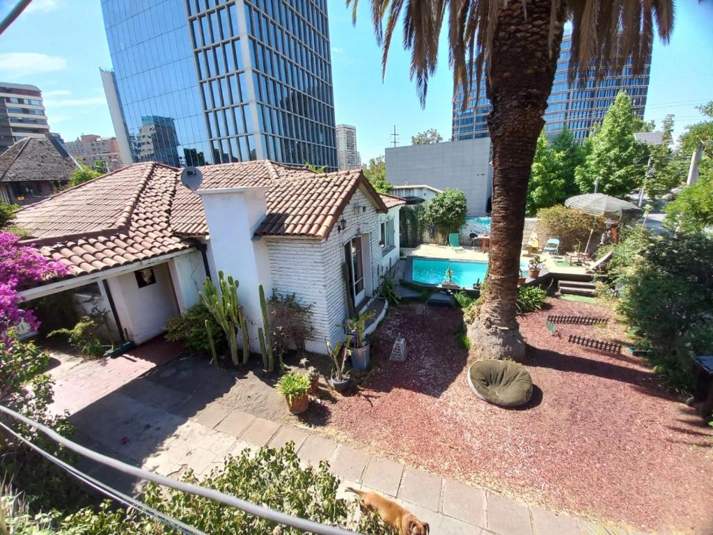 een klein wit huis met een palmboom en een zwembad bij Pieza independiente en casa compartida en Vitacura cn bici y piscina in Santiago