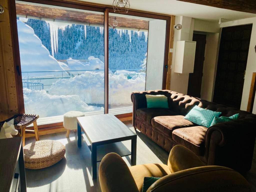 uma sala de estar com um sofá e uma grande janela em Maison des Alpes accès station Les 2 Alpes 1h Grenoble em Vénosc
