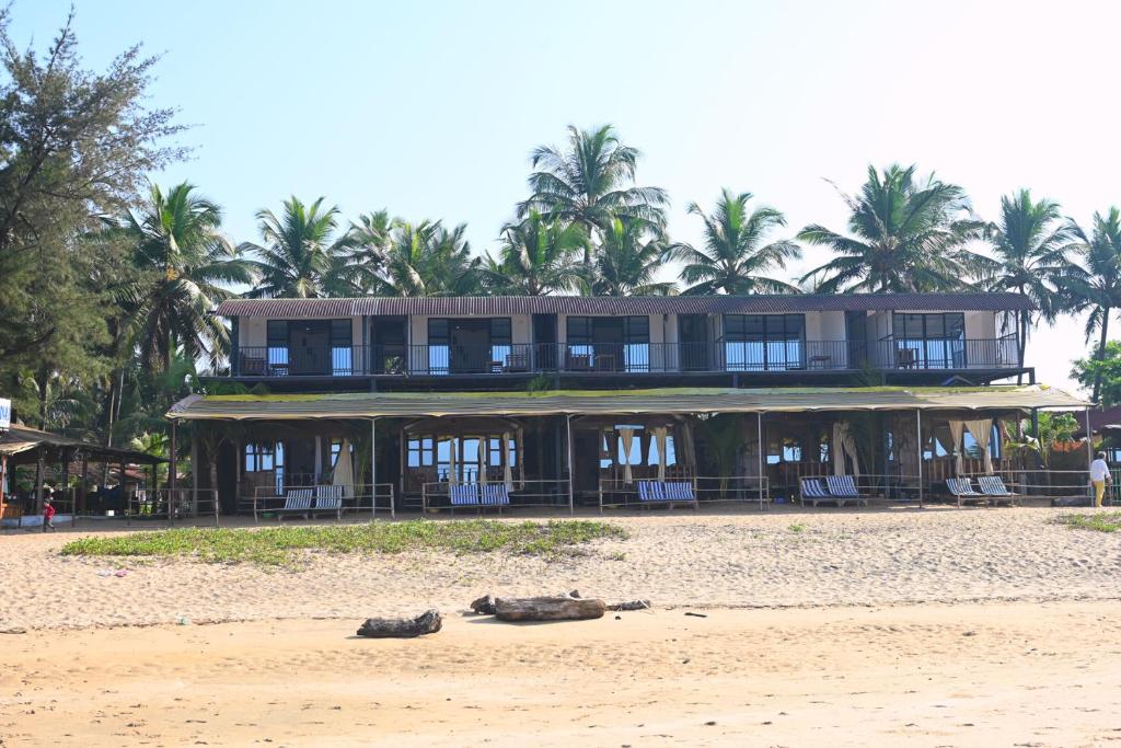 a large building on the beach with shoes on the sand at Madhu Huts Agonda in Agonda