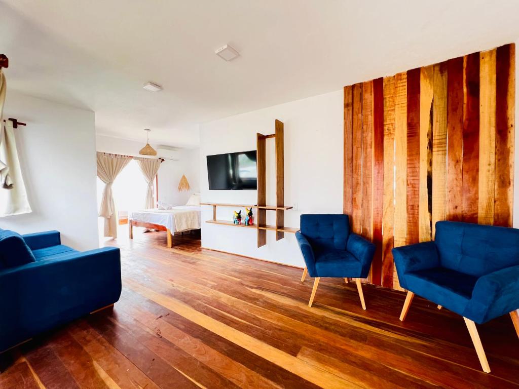 a living room with two blue chairs and a tv at Villa Mar Residence in Jericoacoara