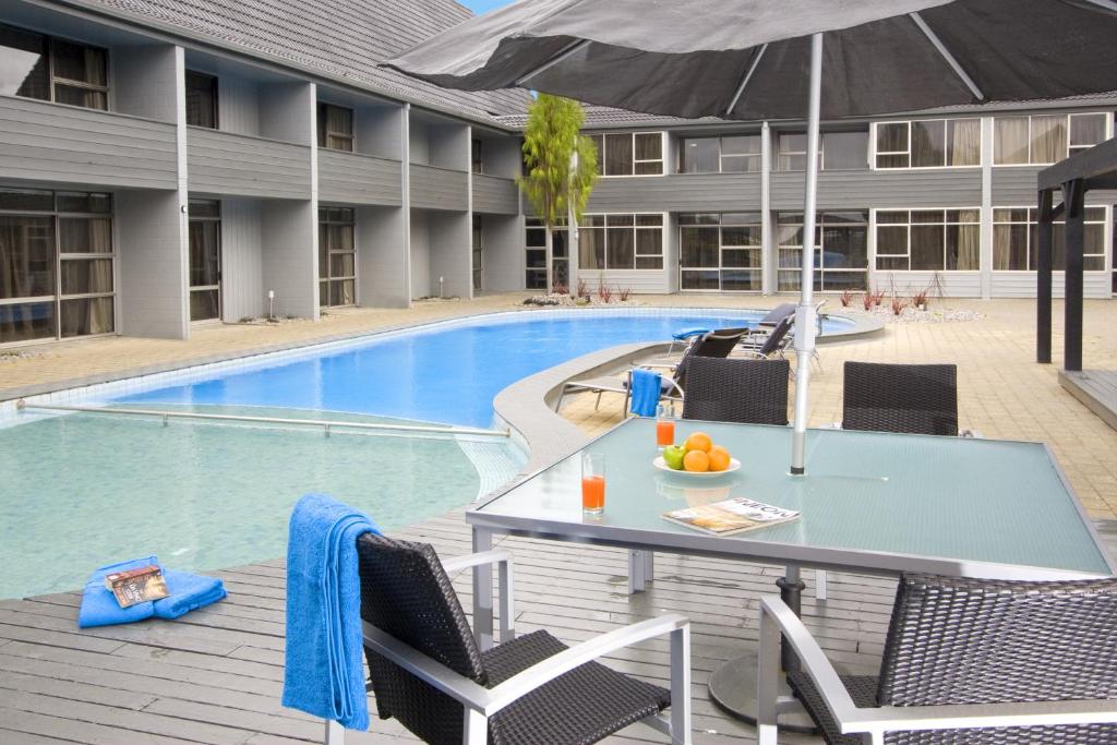 a table with an umbrella next to a swimming pool at Apollo Hotel Rotorua in Rotorua