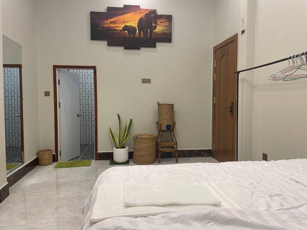 1 dormitorio con cama blanca y espejo en Bun Homestay, en Battambang