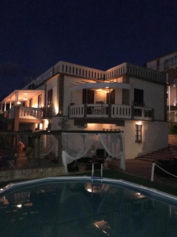 B&B Villa Delle Rondini في فيبو فالينتيا مارينا: بيت ابيض كبير فيه مسبح بالليل