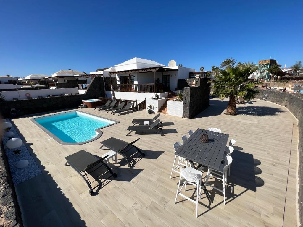 um pátio com uma mesa e cadeiras e uma piscina em Villa Little Star em Playa Blanca