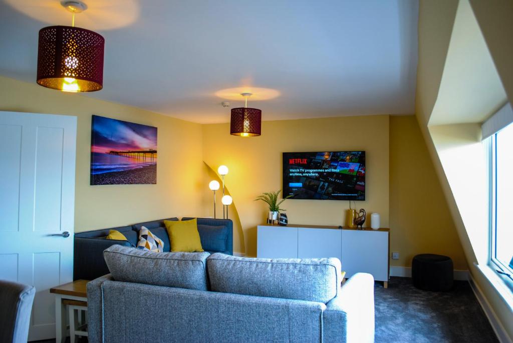 a living room with a blue couch and a tv at Sky Lounge - Beachfront top floor apartment with stunning veiws in Kent