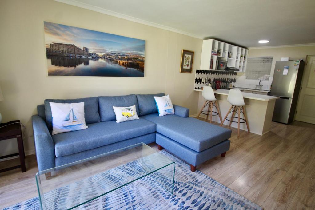 a living room with a blue couch and a kitchen at Tamboerskloof 2 bed apartment in Cape Town