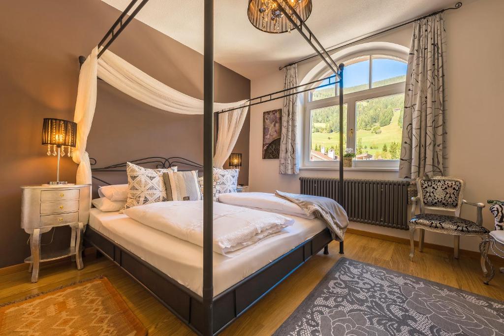 Schlafzimmer mit Himmelbett und Fenster in der Unterkunft Zenana Boutique Hotel in Innichen