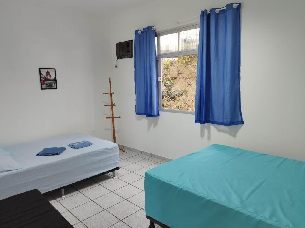 une chambre avec deux lits et une fenêtre avec des rideaux bleus dans l'établissement Seu Apto na Praia da Costa 13 Barato Completo TV Geladeira Fogão Ar Cond Local Excelente Centro, à Vila Velha