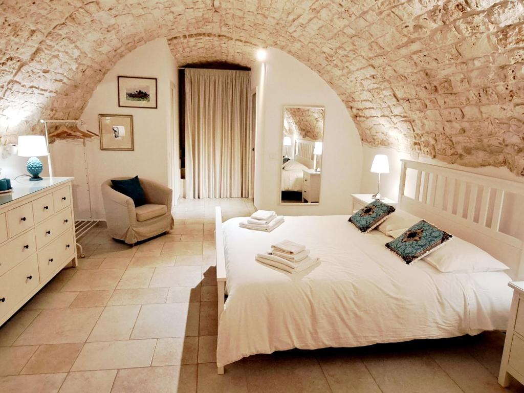 een slaapkamer met een wit bed en een stenen muur bij Dimora Imma in Conversano