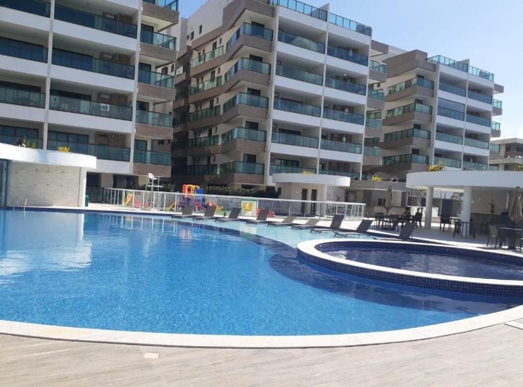 uma grande piscina em frente a um edifício em 2 QUARTOS a 50m PRAIA dos Anjos em Condomínio Club com PISCINA, estacionamento e portaria 24h - Área de lazer 3000m, wi-fi 450MB, churrasqueira e cozinha completa em Arraial do Cabo