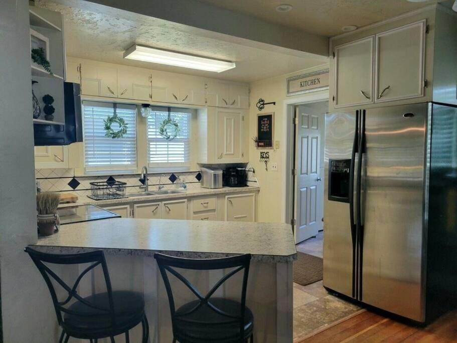 a kitchen with a refrigerator and two bar stools at Mi Casa, Tu Casa in Rupert
