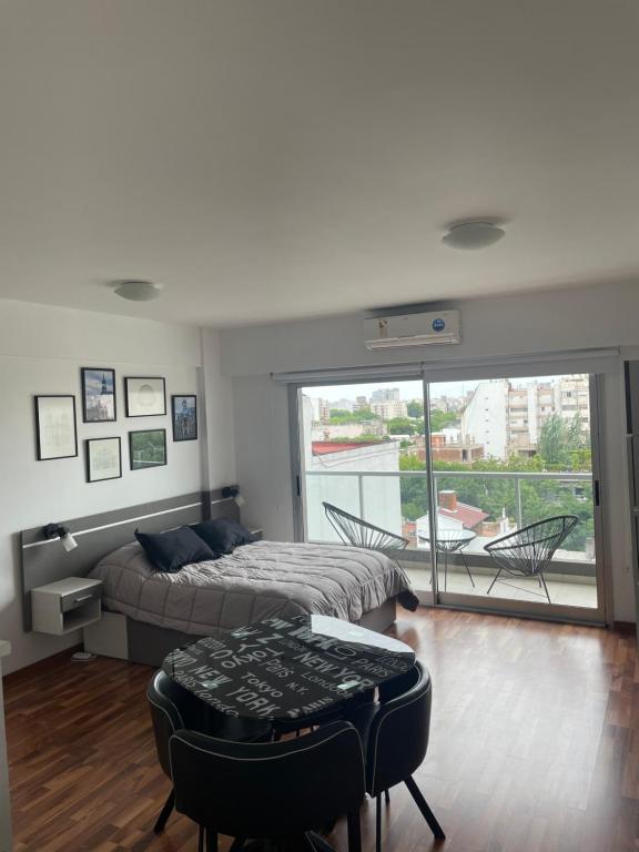 Metropolitan Highline Apartments في بوينس آيرس: غرفة نوم بسرير وطاولة وبلكونة
