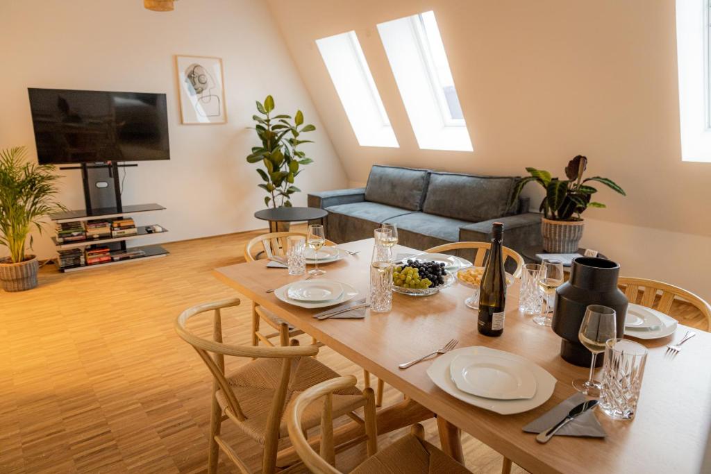 een woonkamer met een tafel met stoelen en een bank bij BONNYSTAY - Downtown - Zentral - 5 Personen - Modern - Luxus - Design in Passau