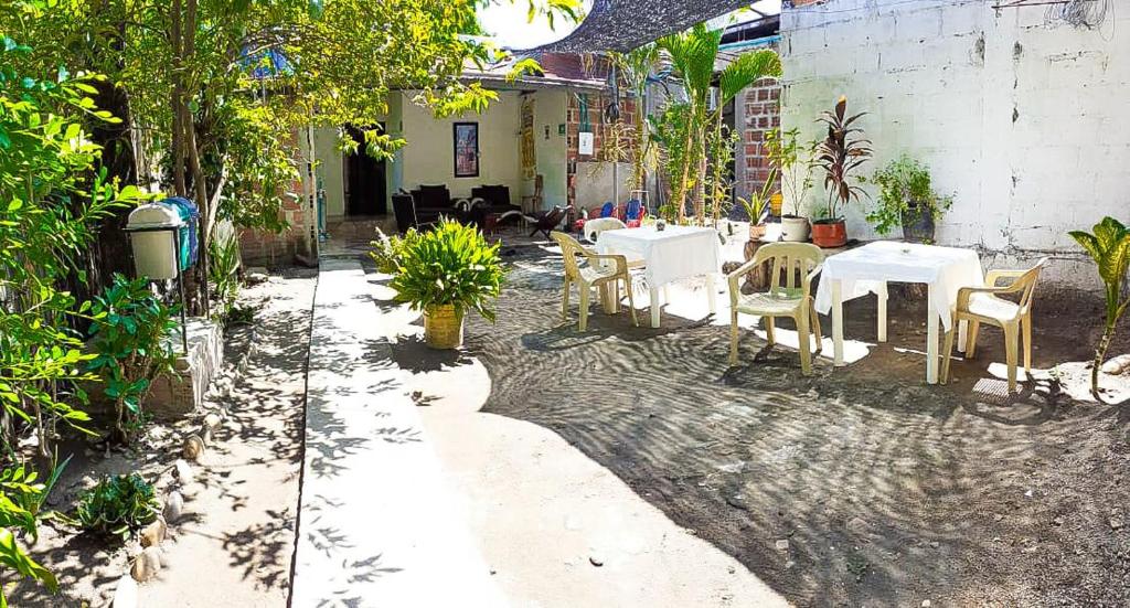 un patio con mesas y sillas blancas, una mesa y sillas en Hostal Villa del Río Las Brisas, en Villavieja