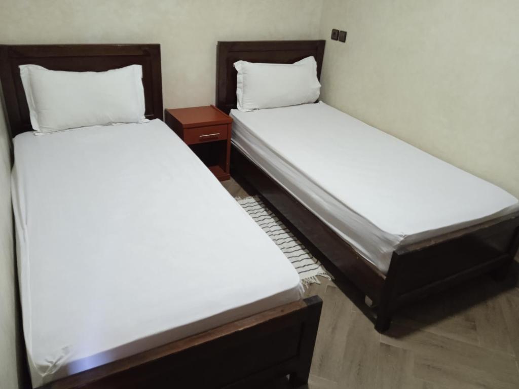 two beds in a small room with white sheets at Résidence Perle De L'océan B.M.L in Mirleft