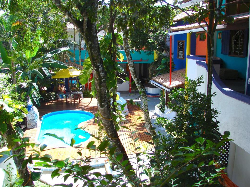 un patio trasero con piscina, árboles y una casa en Art Hotel Aos Sinos Dos Anjos, en Arraial d'Ajuda