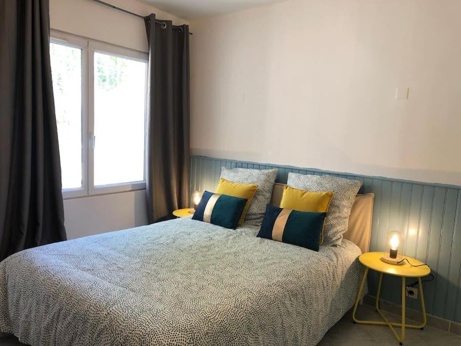 een slaapkamer met een bed met kussens en een raam bij cosy studio design with modern bathroom in Vauréal
