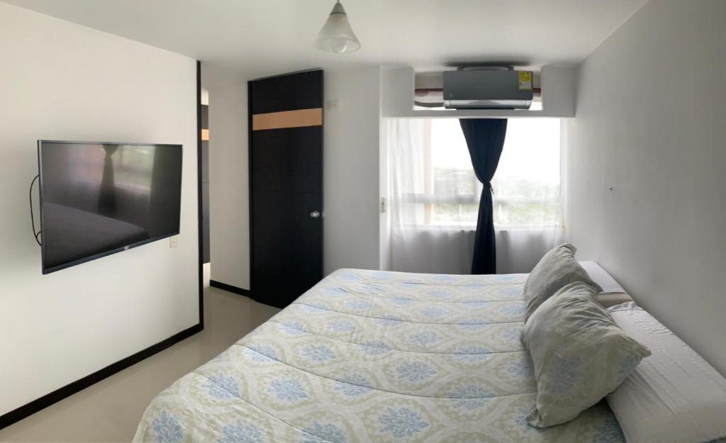1 dormitorio con 1 cama y TV de pantalla plana en Apartamentos Amoblados Cali, en Cali