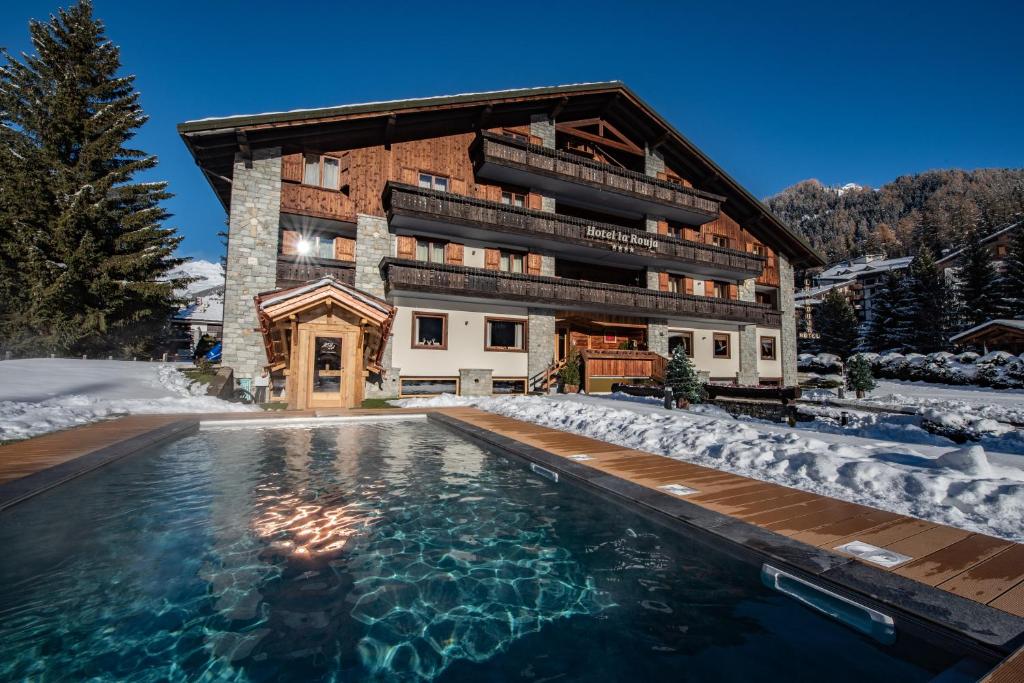 a house with a swimming pool in the snow at Hotel La Rouja in Champoluc