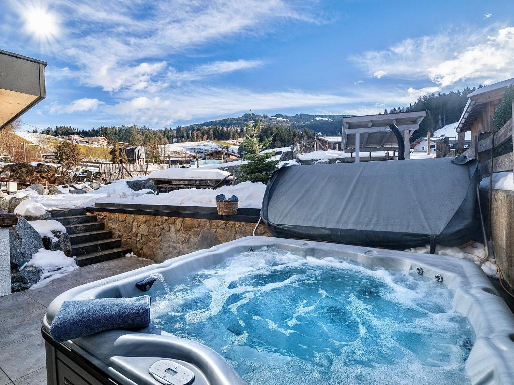 a jacuzzi tub with snow in a yard at das brunn - Luxus Chalet in Kirchberg in Tirol